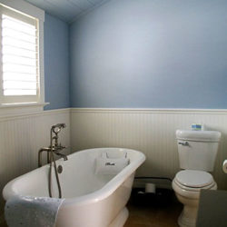 bathroom with traditional looking toilet and bathtub, blue walls with white wainscoting