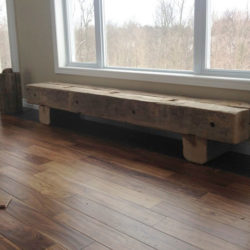 Heavy slab style wooden bench on hard wood floor in front of large picture window.